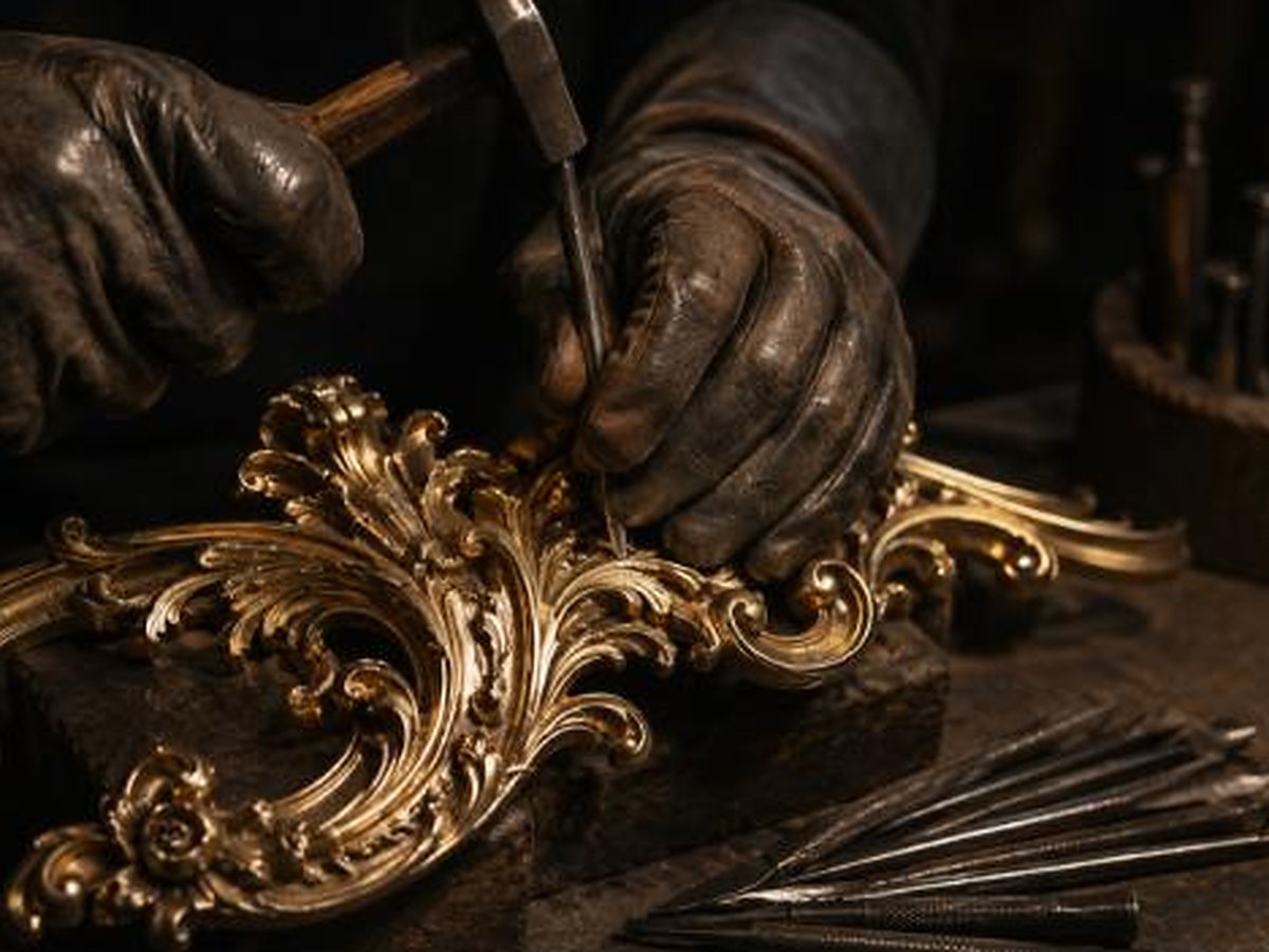 Master artisan hand-chasing a bronze furniture ornament